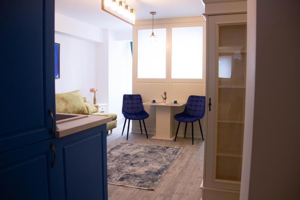 ein Wohnzimmer mit einem Tisch und blauen Stühlen in der Unterkunft Blue Joy Bukovina Aparthotel in Suceava
