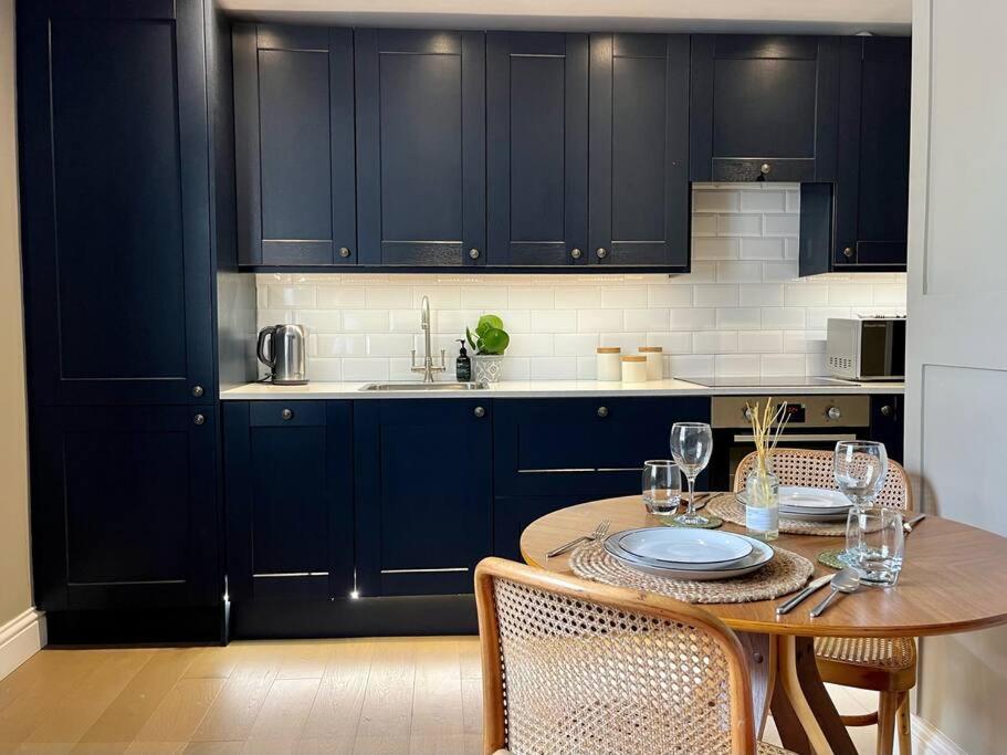 a kitchen with dark blue cabinets and a wooden table at Georgian boutique apartment in central Bath in Bath
