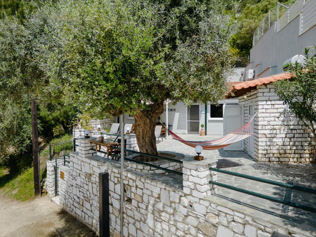 una casa con un albero e un'amaca appesa a un muro di Kritamos Luxury Apartment a Chrisi Ammoudia