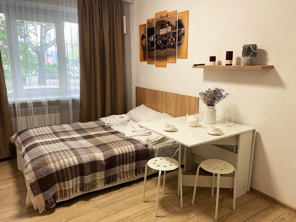 um quarto com uma cama e uma mesa com dois bancos em MYFREEDOM Апартаменти метро Академмістечко ТЦ Lavina Mall em Kiev