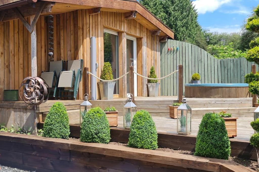 Una casa con un deck de madera con un banco y plantas. en The Wendy house, en Parkend