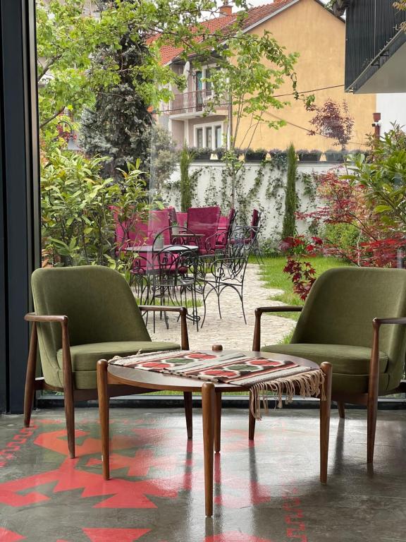 Etnomania Boutique Hotel في بريشتيني: غرفة بها كرسيين وطاولة وفناء