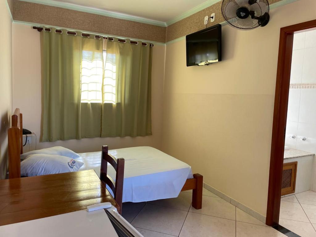 a bedroom with a bed and a table and a television at Pousada Cabana in Avaré