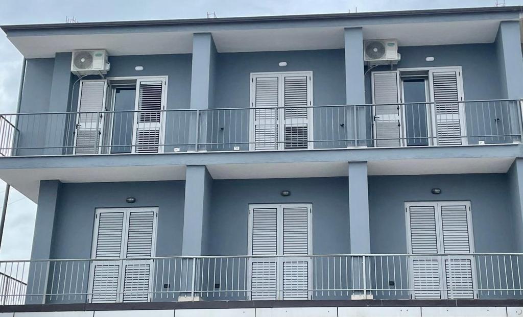 ein blaues Gebäude mit weißen Balkonen und Fenstern in der Unterkunft H&A Guest House in Divjaka