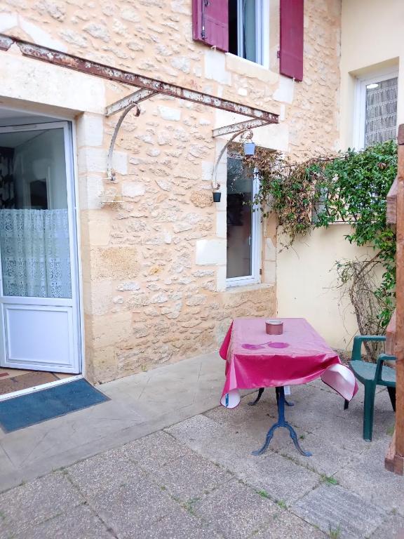 a table with a pink table cloth sitting in front of a building at Studio avec jardin clos et wifi a Langon in Langon