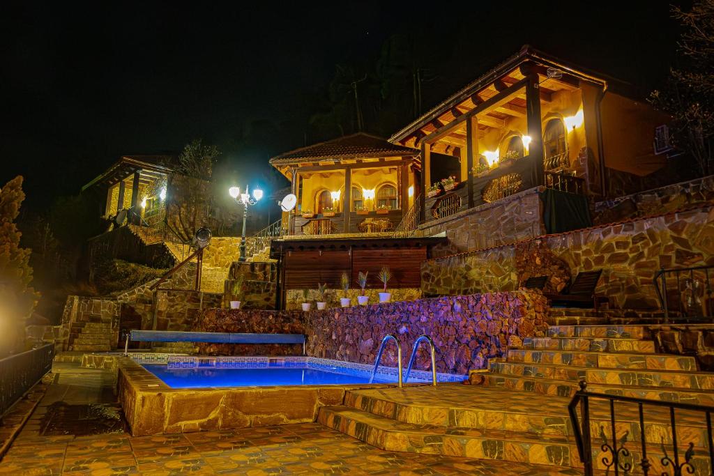 a house with a swimming pool at night at Safari Village Velingrad in Velingrad