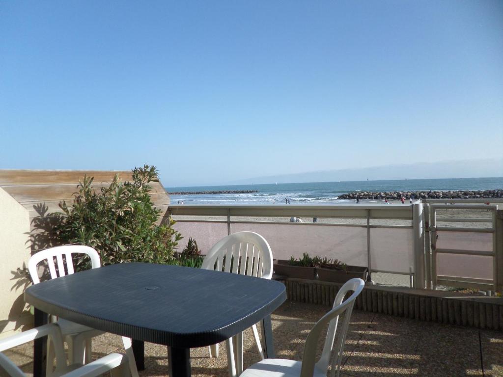 een tafel en stoelen op een balkon met uitzicht op het strand bij Appartement Mauguio-Carnon, 1 pièce, 4 personnes - FR-1-715-16 in Mauguio