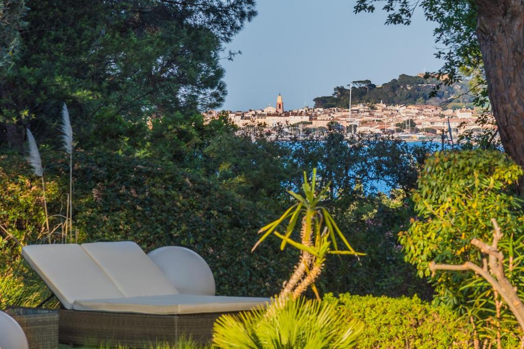 a white couch in a garden with a view of a city at Les Capucines Saint Tropez in Saint-Tropez