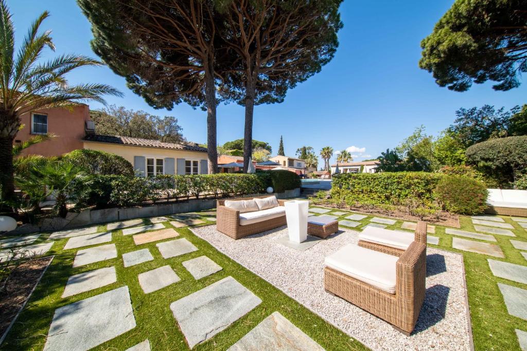 a patio with chairs and tables in a yard at Les Capucines Saint Tropez in Saint-Tropez