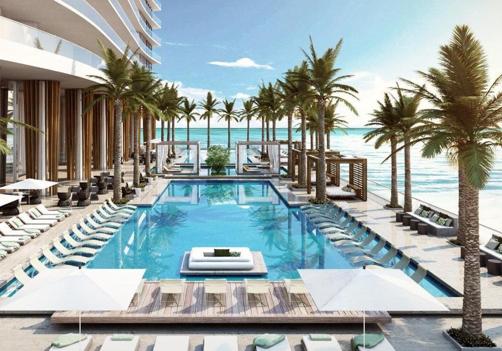 ハリウッドにあるOceanfront Condo Direct Ocean & Beach Club Accessのヤシの木と椅子が備わるビーチのプール