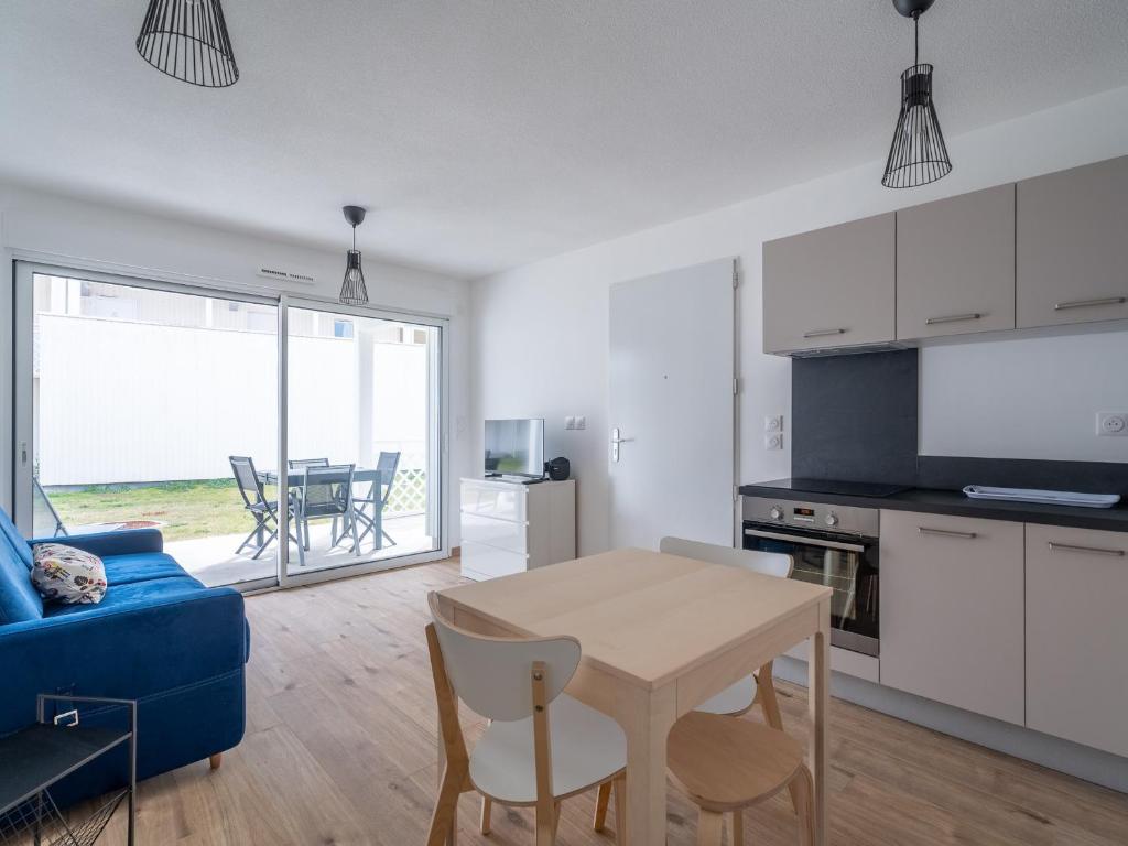 un salon avec une table et un canapé bleu dans l'établissement Appartement Neuf 3* à Mimizan - 100m de l'Océan, Piscine, Clim, WiFi, 4 Pers, Ménage inclus - FR-1-50-112, à Mimizan