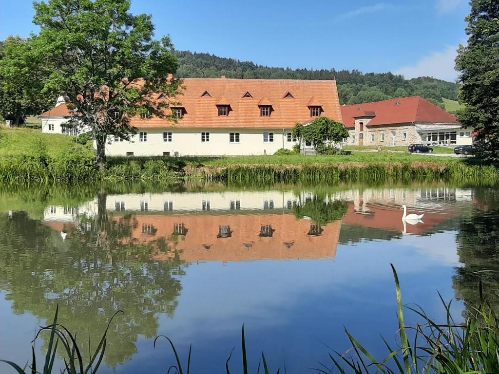 a building with a reflection in the water at Apartmán v lokalitě statku ve Vrhavči in Vrhaveč