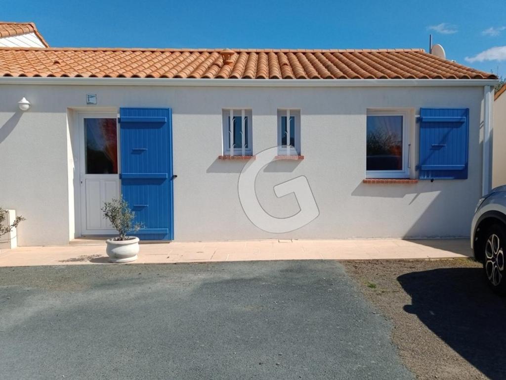 une maison avec portes bleues et une voiture garée devant dans l'établissement Maison de vacances à La Tranche-sur-Mer, 800m plage, commerces à pied, terrasse, parking, 4 pers - FR-1-357-302, à La Tranche-sur-Mer