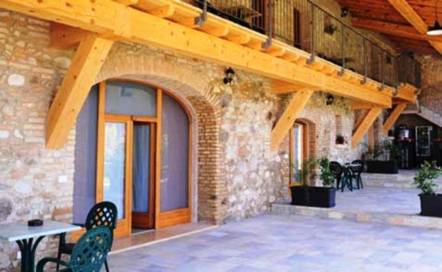 eine Terrasse mit einem Tisch und Stühlen sowie ein Gebäude in der Unterkunft Agriturismo Corte La Sacca in Pozzolengo
