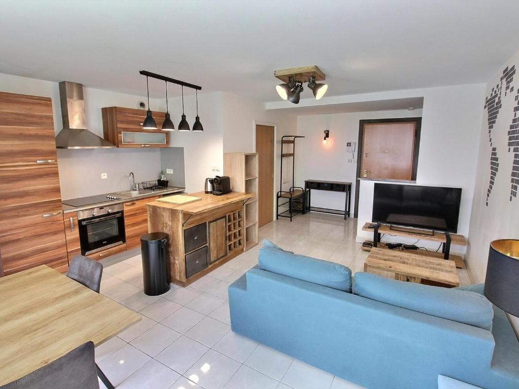 un salon avec un canapé bleu et une cuisine dans l'établissement Appartement lumineux à Colmar avec terrasse, parking et WiFi – 5 min du centre - FR-1-722-1, à Colmar