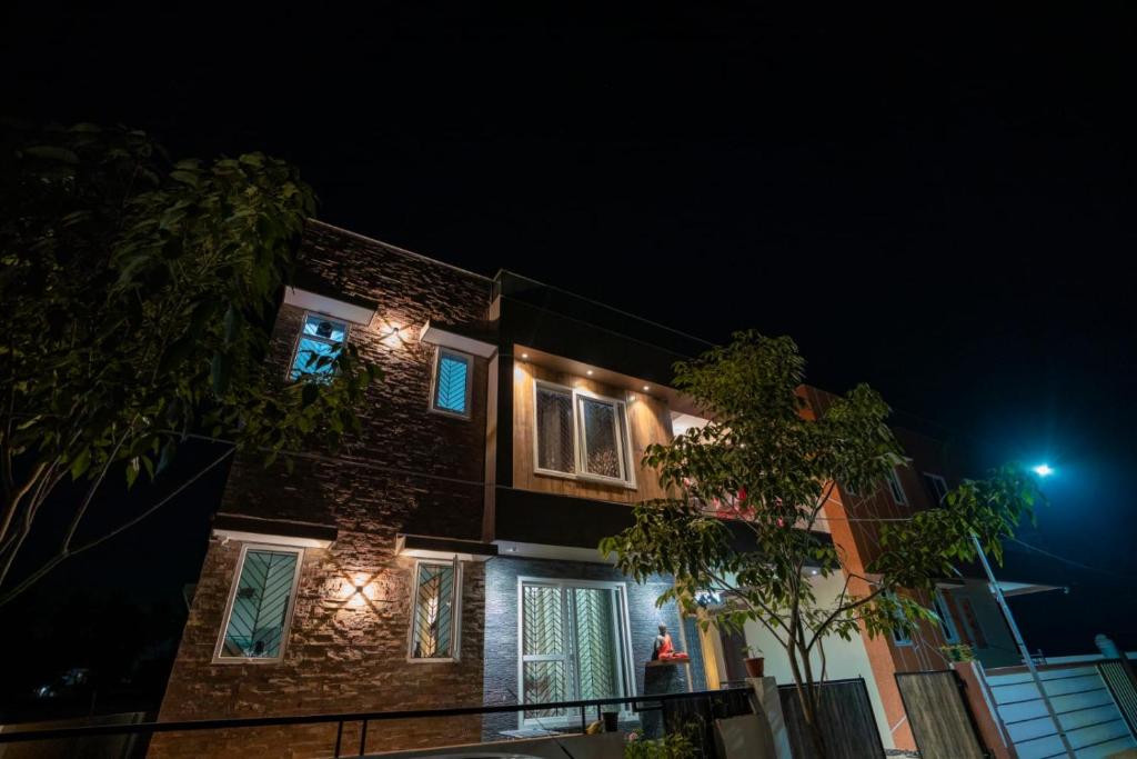 uma casa de tijolos com luzes acesas à noite em Manasvi em Mangalore