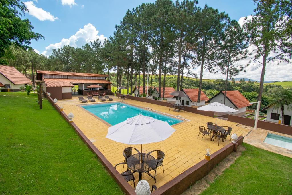 ein Bild eines Pools mit Tischen und Sonnenschirmen in der Unterkunft Hotel Dona Paschoalina in Socorro