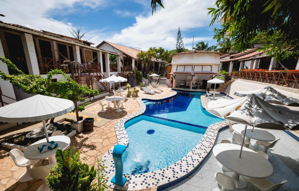 a pool with chairs and umbrellas next to a building at Pousada Bicho Preguiça in Pipa