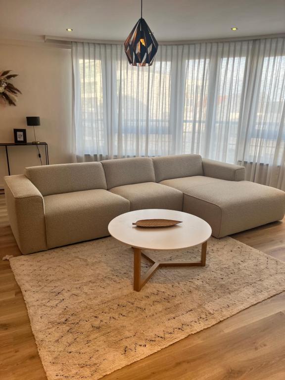 een woonkamer met een bank en een salontafel bij Portofino - luxe appartement met lateraal zeezicht in Oostende