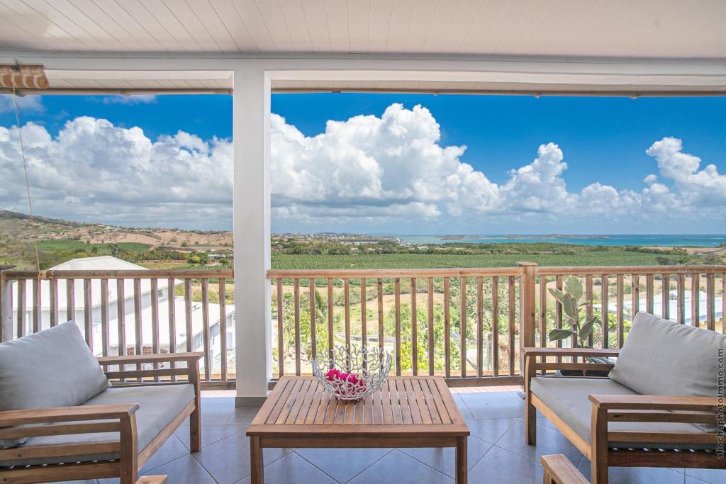 eine Veranda mit einem Tisch und Stühlen sowie Meerblick in der Unterkunft Haut de villa au François in Le François