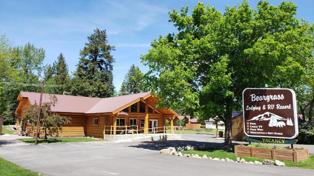 a log cabin with a sign in front of it at Beargrass Lodging & RV Resort in Hungry Horse