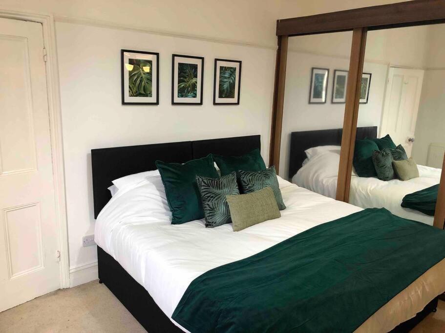 ein Schlafzimmer mit einem großen Bett mit grünen Kissen in der Unterkunft 7 Bed Home*Contractors*CityCentre*FREE Parking in Derby