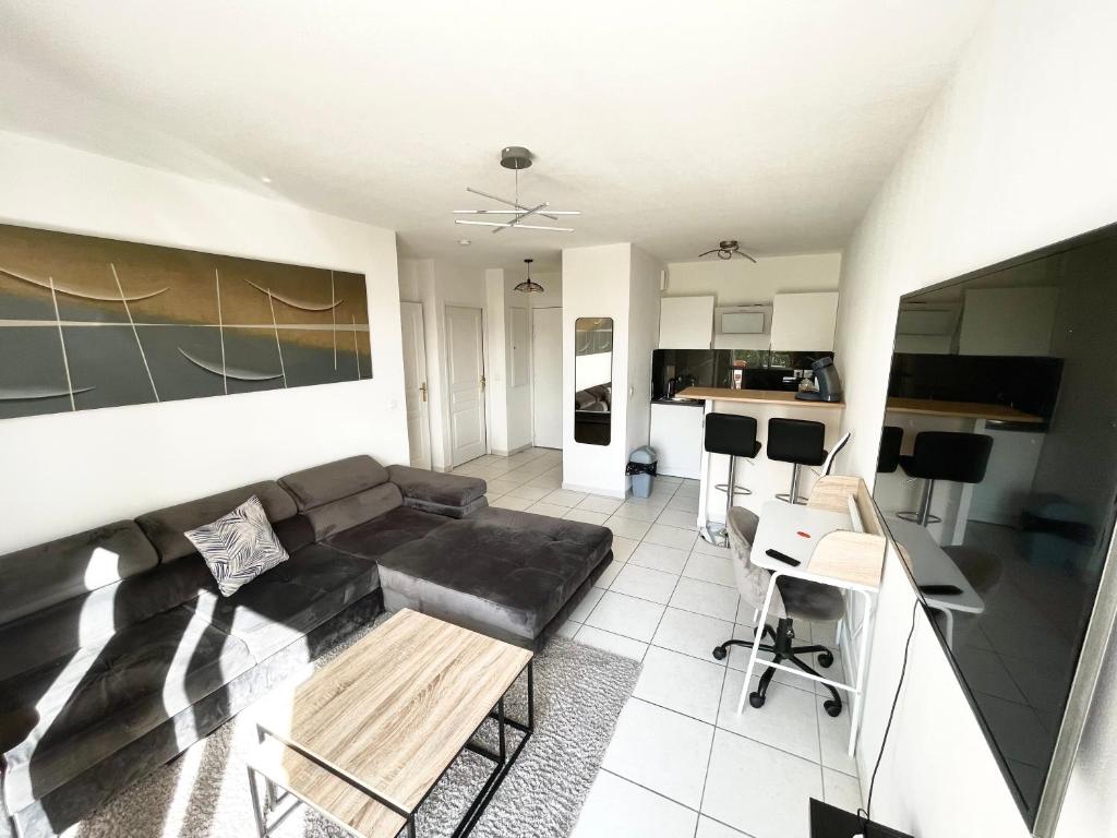 ein Wohnzimmer mit einem schwarzen Sofa und einer Küche in der Unterkunft T2 Cosy Montpellier in Montpellier