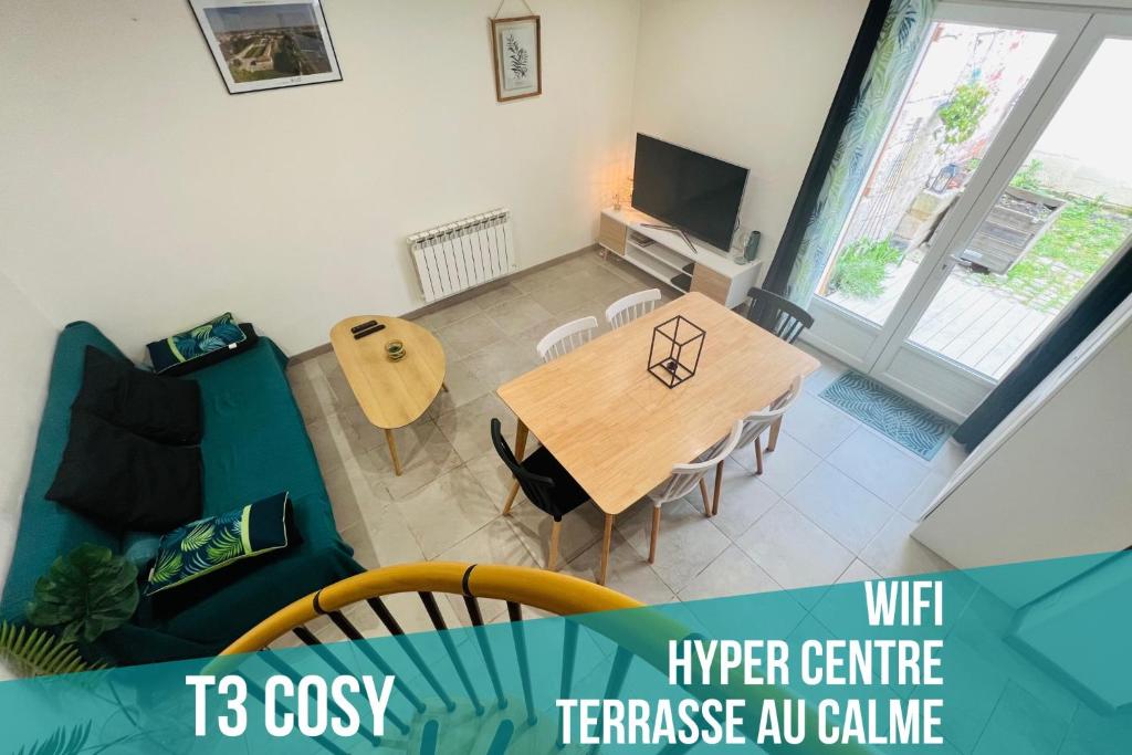 a living room with a table and a blue couch at T3 COSY MAISON DE VILLE TERRASSE AU CALME in Rochefort