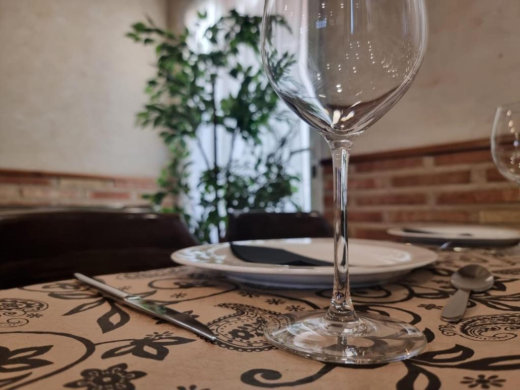 einen Tisch mit einem Weinglas und Platten darauf in der Unterkunft Hostal Restaurante CASA FRAN in La Pueblanueva