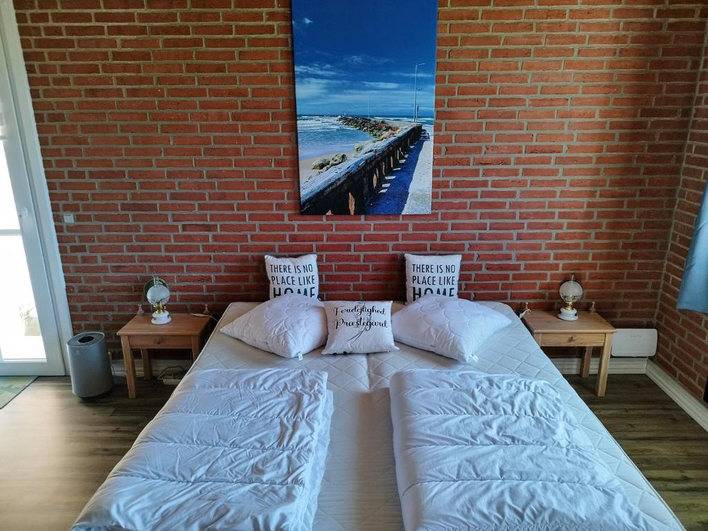 a bedroom with a bed and a brick wall at Ferielejlighed Rubjerg Præstegård in Løkken