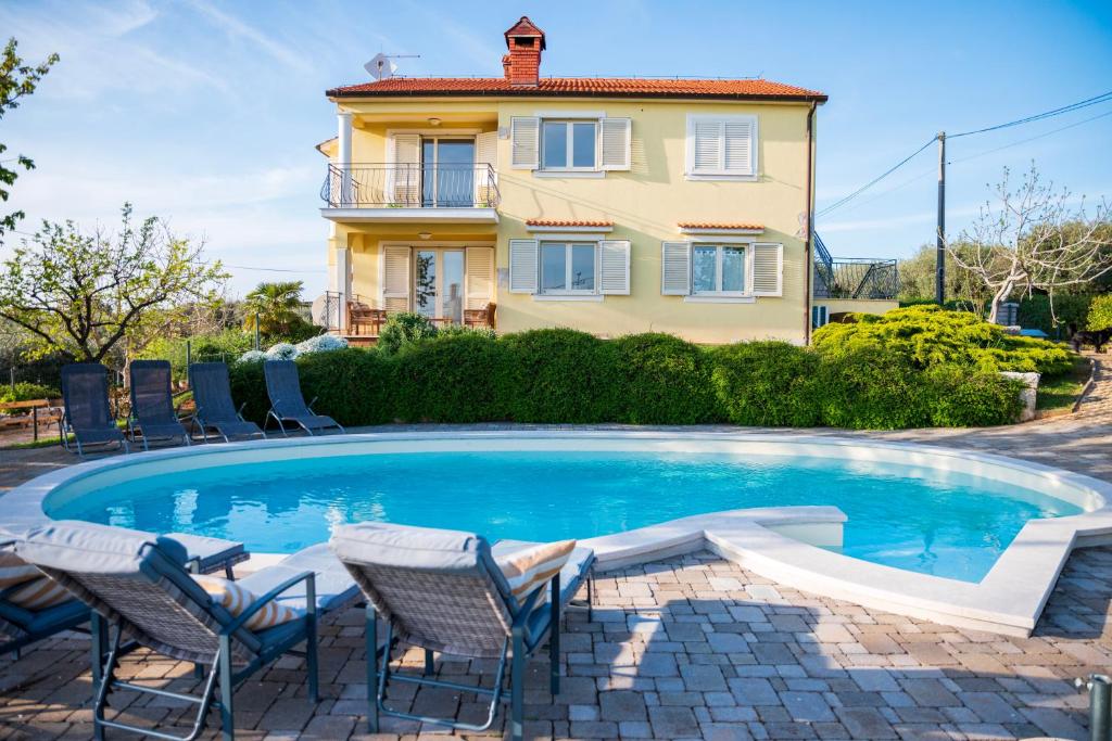 a pool with chairs and a house in the background at Apartment Laetitia in Kaštelir