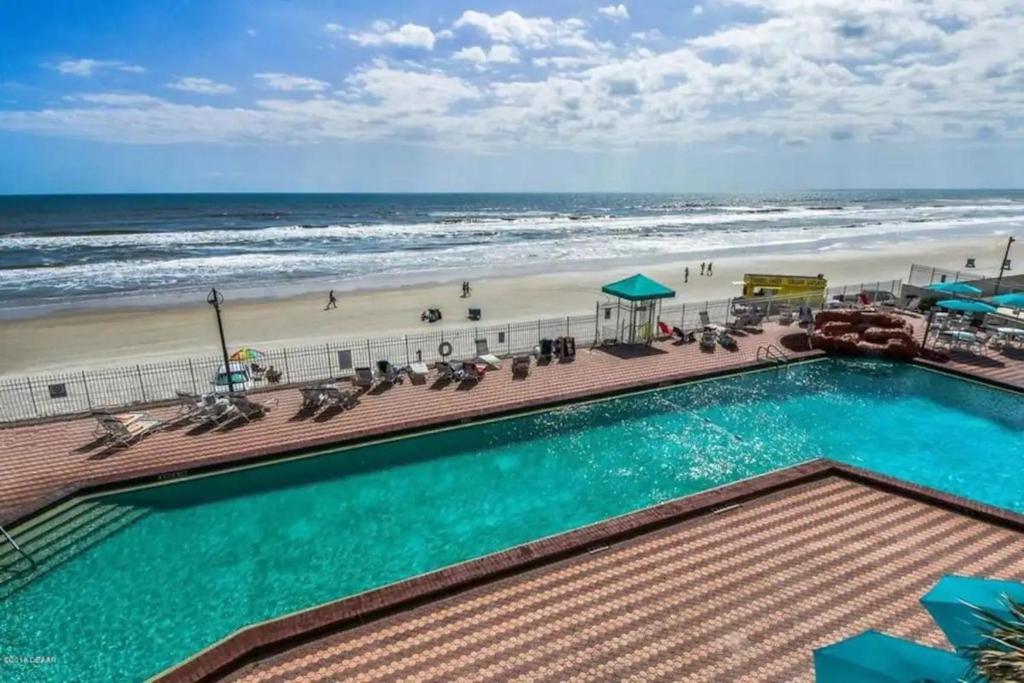 una piscina junto a una playa con el océano en Amazing Studio on Daytona Beach en Daytona Beach