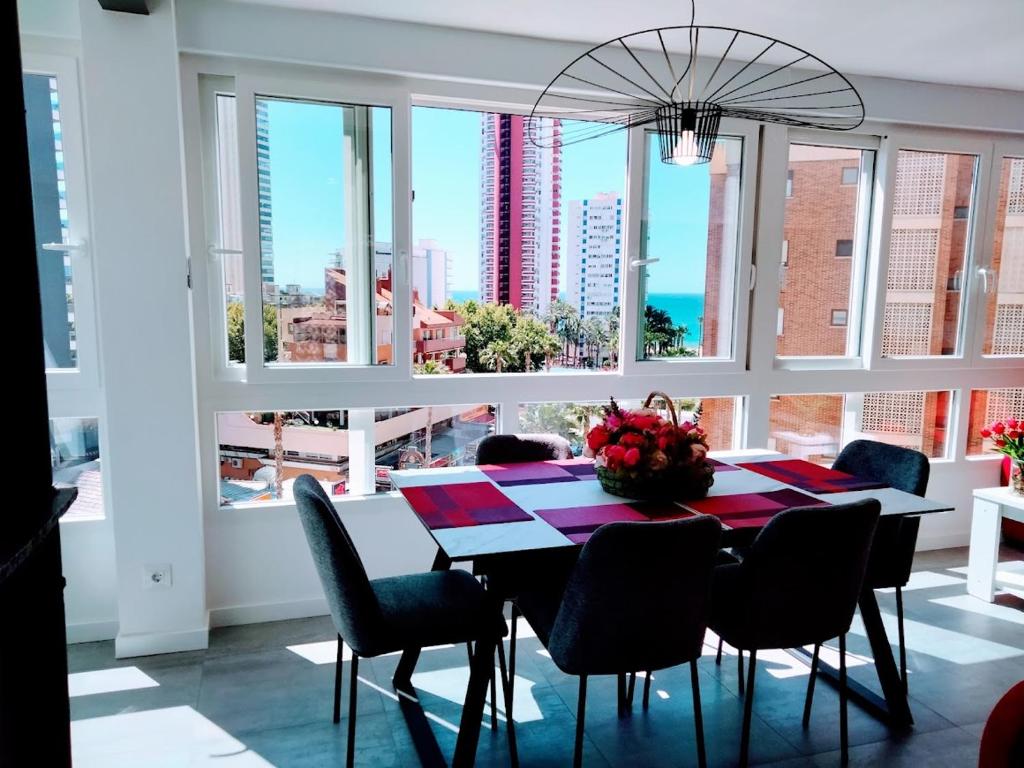 a dining room with a table and chairs and windows at CASA MI LOLA in Benidorm