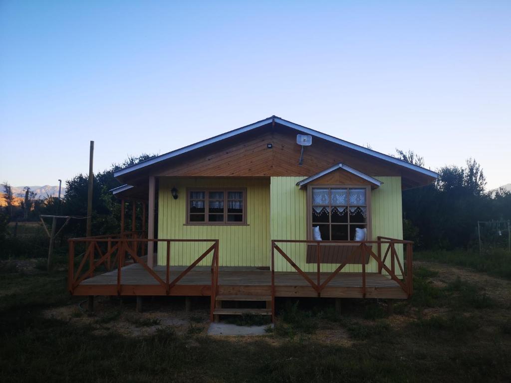 a small yellow house with a porch and a deck at Cabaña Jacarandá in Salamanca