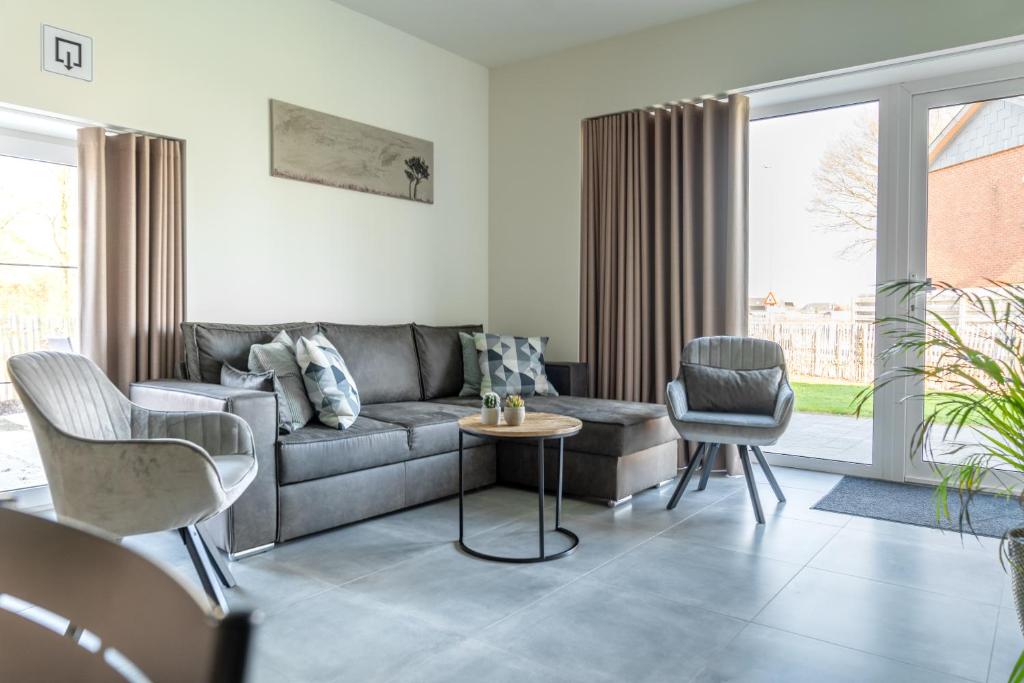 a living room with a gray couch and chairs at De Hoog Velden 12 in Pelt
