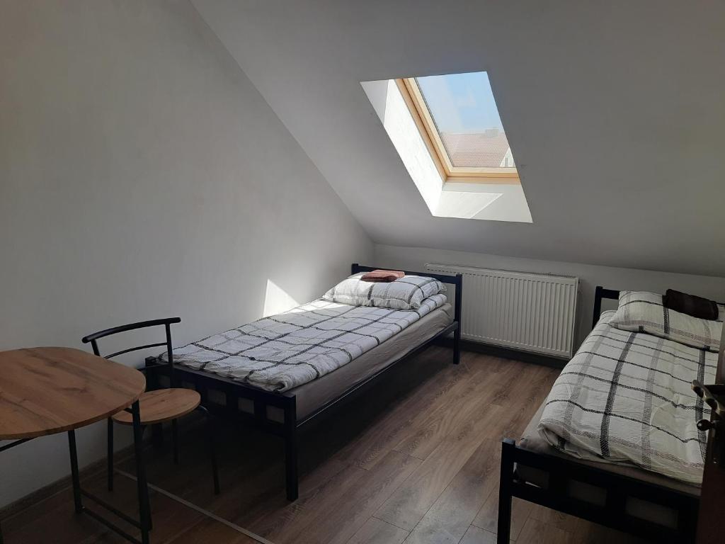 een kamer met 2 bedden, een tafel en een raam bij Pokoje in Tczew