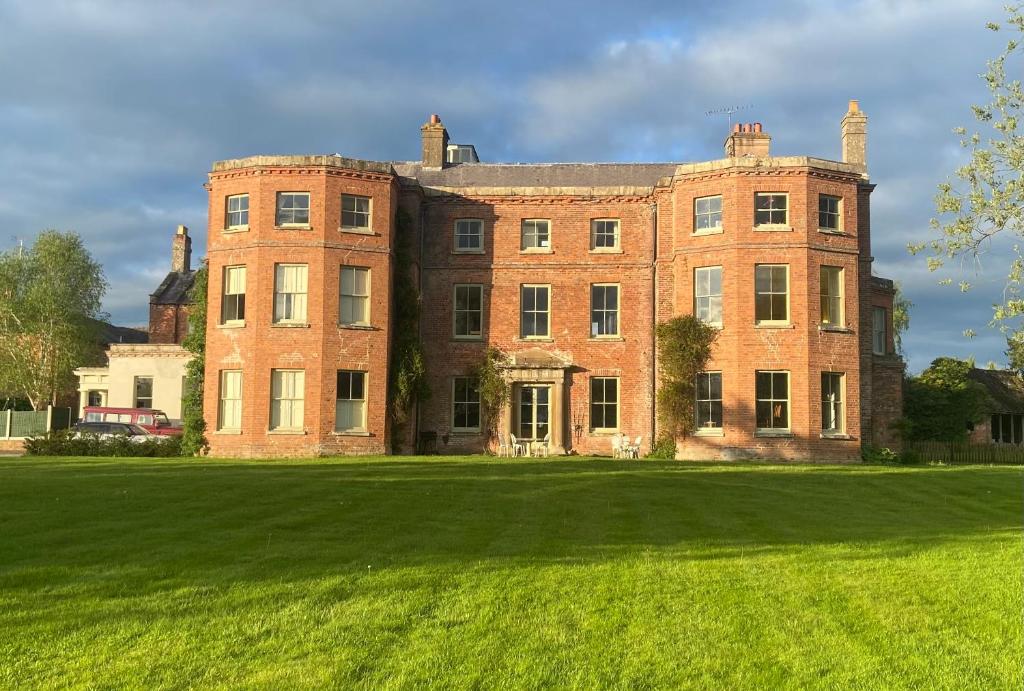 a large brick building with a large grass field at Caynham Court in Ludlow