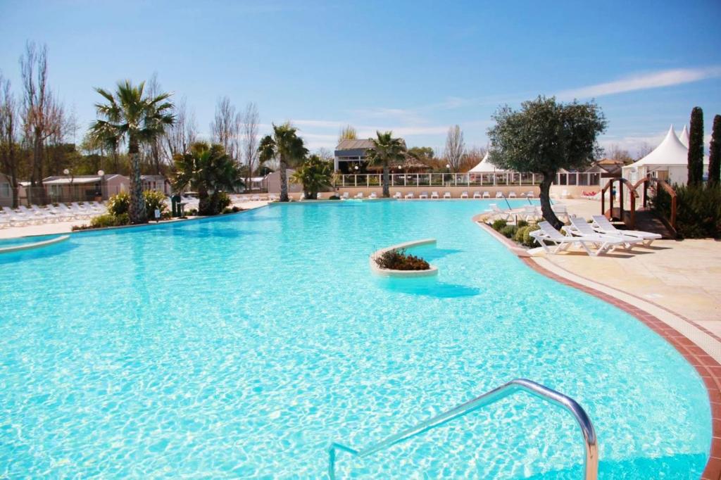 uma grande piscina com água azul num resort em Mobil-Home Clos 14 à VIAS em Vias
