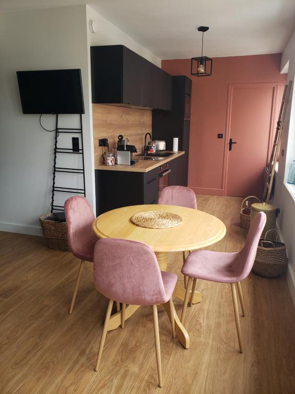 a kitchen with a wooden table and pink chairs at Le Paille en Queue in Fouesnant