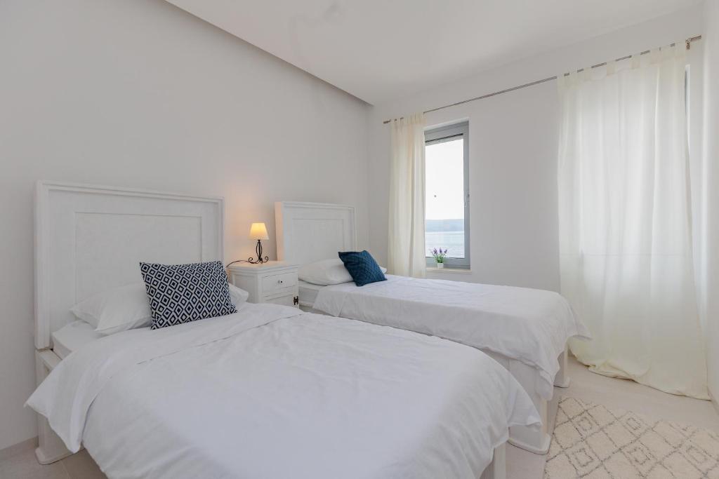 Cette chambre blanche dispose de 2 lits blancs et d'une fenêtre. dans l'établissement Luxury Apartment Slavica by the sea,with garden, à Sukošan
