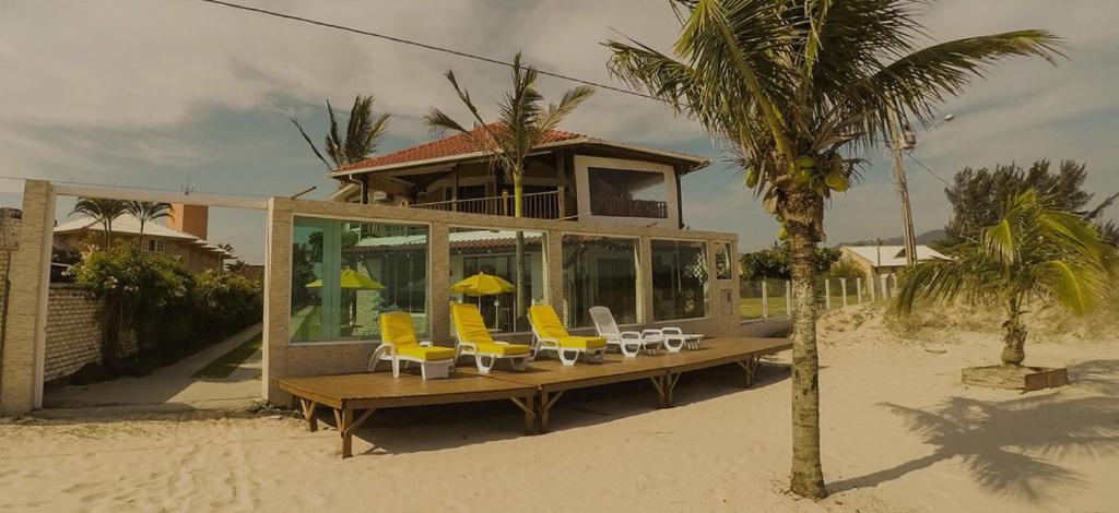 a house on the beach with yellow chairs and a table at Pousada Recanto Edênico in Palhoça