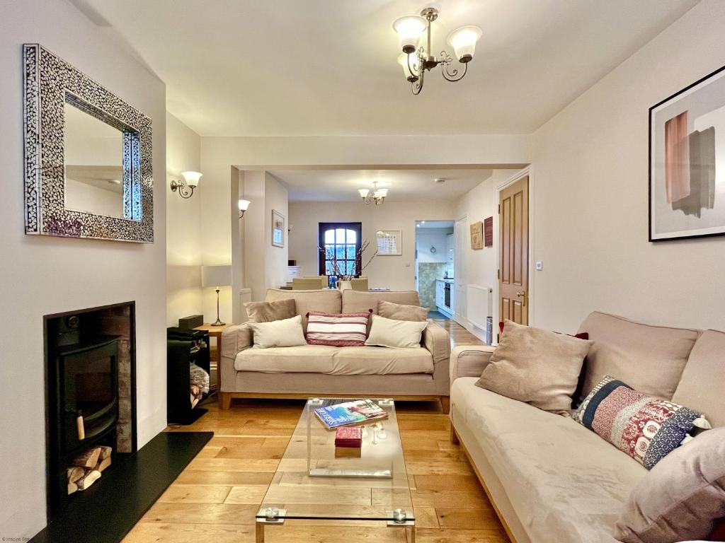 a living room with two couches and a fireplace at Wickland Cottage in Chichester