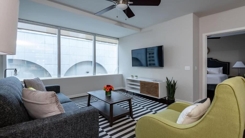 ein Wohnzimmer mit einem Sofa, Stühlen und einem TV in der Unterkunft CozySuites TWO Modern Apartments SKY POOL in Dallas