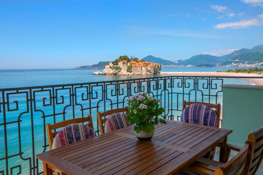 a wooden table with a vase of flowers on a balcony at Montesan Luxury Apartment DOO ODMONTE in Sveti Stefan