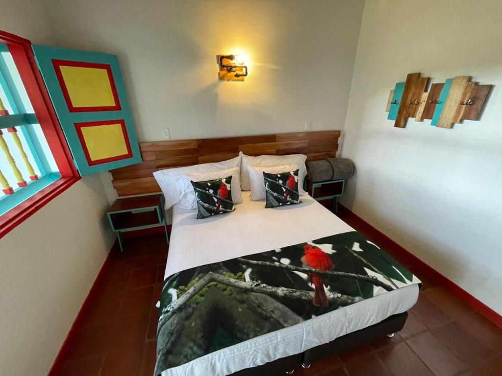 a bedroom with a bed with a red bird on it at Hotel Momotus Cocora in Salento