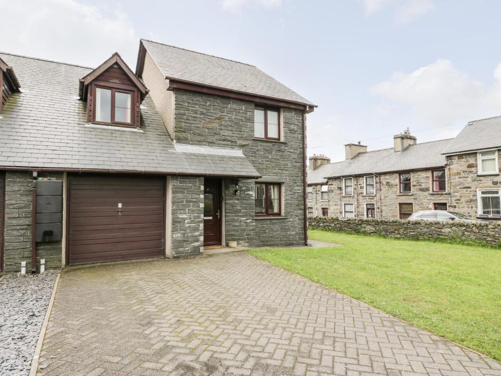 a brick house with a garage and a grass yard at 6 Stad Yr Ysgol in Blaenau-Ffestiniog