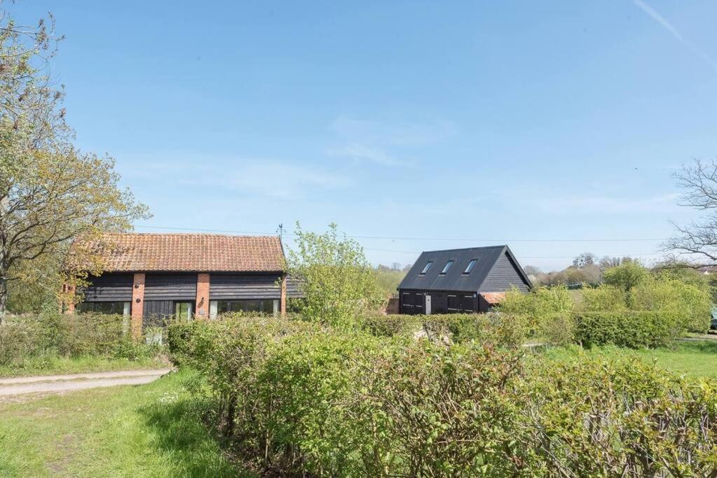 una casa con un tetto nero in un campo di Yoxford Farm Hayloft a Saxmundham