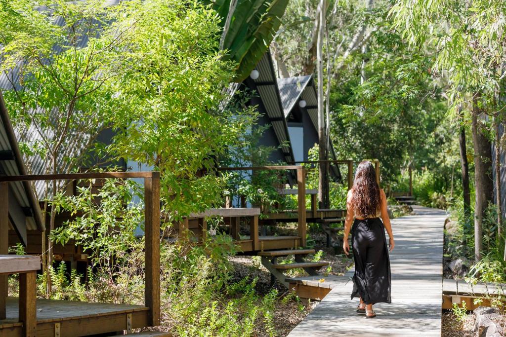 a woman walking down a path through a garden at Selina Magnetic Island in Horseshoe Bay