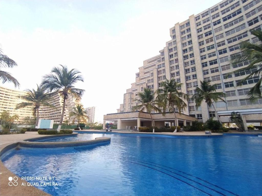 una gran piscina frente a un gran edificio en Ocean Blue en Porlamar