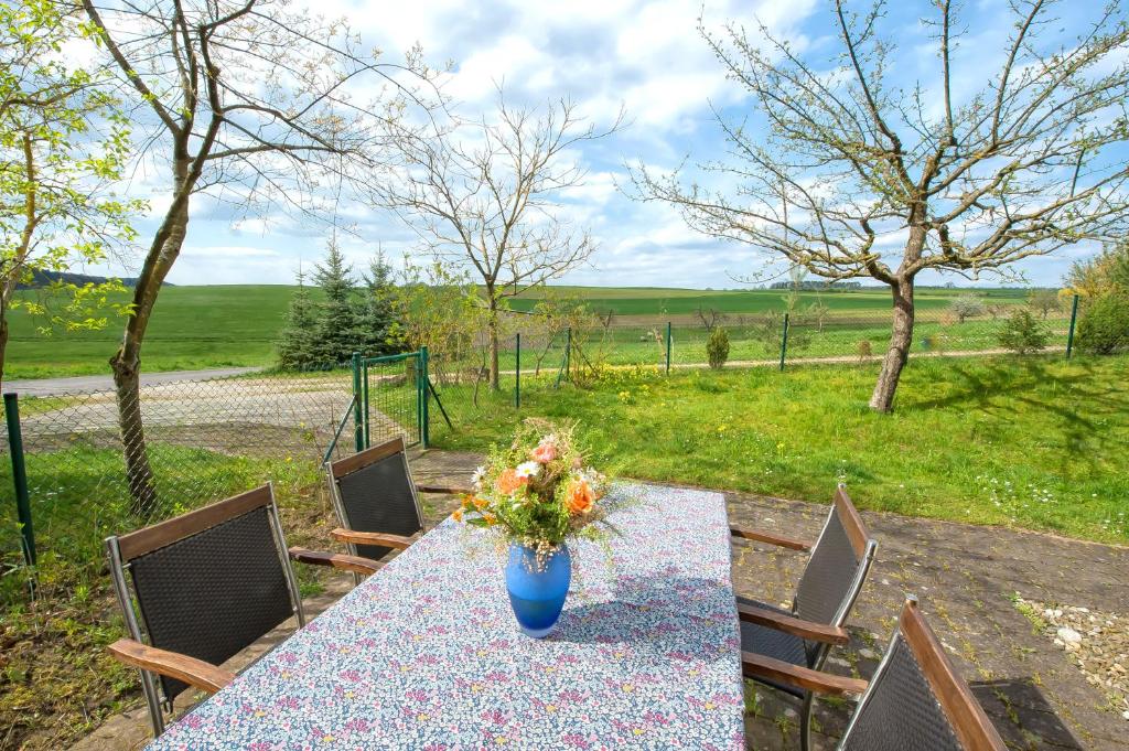 einen Tisch mit einer blauen Vase mit Blumen darauf in der Unterkunft Iris in Walsdorf